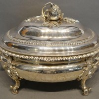 A George III Silver Soup Tureen, the cover mounted with an opening pomegranate above a two handled tureen with four scroll feet bearing engraved crest Hammer £4,800